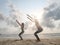 Two women practice chair yoga asana at seashore in sunlight