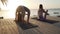 Two women practice yoga in seaside hotel lounge zone at sunset