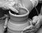 Two women in process of making clay vase on pottery wheel