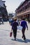 Two women in purple blouses pass by temple square.