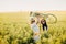 two women in a rapeseed field with a bicycle enjoy a walk in nature rejoicing