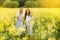 two women in a rapeseed field with a bicycle enjoy a walk in nature rejoicing