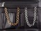 Two women`s chain necklaces with on female black leather cosmetic bag