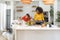 Two women share a jovial moment in the homely kitchen. Amidst their laughter, a Siberian Husky sits attentively with hopeful eyes