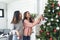 Two Women siblings using hands decorate Christmas tree red ball, bauble, snow flake. Close up hands holding red ball bauble