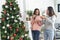 Two Women siblings using hands decorate Christmas tree red ball, bauble, snow flake. Close up hands holding red ball bauble