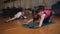 Two women on the sports training in the gym. Performing Pilates exercises on a special Mat on the floor.