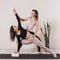 Two women in sportswear, practicing yoga, do a low lunge on one leg with a twist or Anjanasana, crescent pose