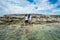 Two women standing in the ocean near garbage dump and holding hands