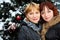 Two women stands near green tree with snow