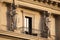 Two women stautes, caryatids,  around a balcony during sunset