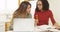 Two women students studying in kitchen with laptop computer