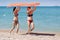 Two women in swimsuits carrying inflatable raft over their heads