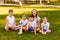 Two women and three children sit on green grass