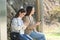 Two women waiting in a bus stop checking phone