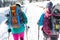 Two women walk with snowshoes on the backpacks, winter trekking