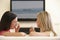 Two Women Watching Sad Movie On Widescreen TV At Home