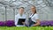 Two women in white coats and black aprons. Scientists, biologists or agronomists examine and analyze flowers and green