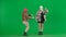 Two women in white and pink balaclavas dancing merrily. Freak women in fur coats on green studio background. Fashion