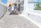 Two women in white striped clothes walking towards in whitewashed alleyway past shops