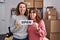 Two women working at small business ecommerce holding open banner sticking tongue out happy with funny expression