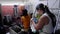 Two women working in a team in a small local winery, one is capping bottles, and the other one is bottling wine