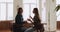 Two women workmates lead conversation sit at desk in office