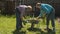 Two women in the yard putting firewood in a wheelbarrow