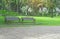 Two wooden bench on fresh green carpet grass yard, smooth lawn beside gray concrete block pavement walkway