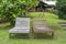 Two wooden deck chairs on the green grass near the home on the tropical island of Borneo, Malaysia
