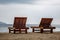 Two wooden empty deck chairs on the beach. Overcast