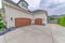 Two wooden garage doors with large driveways and concrete fence