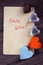 Two wooden hearts, chocolates and a note with the words love you on a wooden background. Greeting card for Valentine`s day.