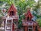 Two wooden spirit houses in a tropical garden