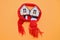 Two wooden toy houses with windows in a red scarf on a orange background, warm house, insulation of houses, copyspace