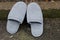 Two wool gray slippers stand at the curb on the asphalt