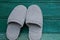 Two wool gray slippers stand at the green wooden wall
