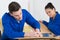 Two worker in blue dungarees in carpenters workshop