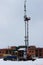 Two workers assemble equipment for telecommunications on the tower with the help of the lift in the winter