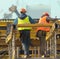 Two workers build metal scaffolding on construction site