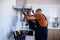 Two workers, handyman in uniform installing or repairing a kitchen extractor, replacing filter in cooker hood