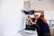 Two workers, handyman in uniform installing or repairing a kitchen extractor, replacing filter in cooker hood