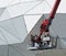 Two workers with helmets and protective suits on a cherry picker do cleaning and maintenance outside a modern metal building