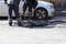 Two workers are leveling the crumb of asphalt in the pit with a drag-roller before the paving with a road mini building roller.