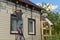 Two workers polish the apartment building with vinyl siding