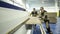 Two workers sawing wooden board on industrial machine. Action. Men in overalls hold board on cutting machine at