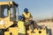 Two workers talking in work break on steamroller bulldozer vehicle