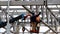 Two workers weld metalwork at height using an industrial elevator.