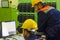 The two workers in yellow helmets in control panel in the laboratory