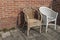 Two worn wicker chairs standing by a surrounded wall